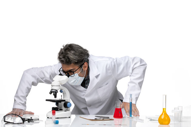 工作前视图中年科学家穿着特殊的白色西装使用显微镜显微镜使用人