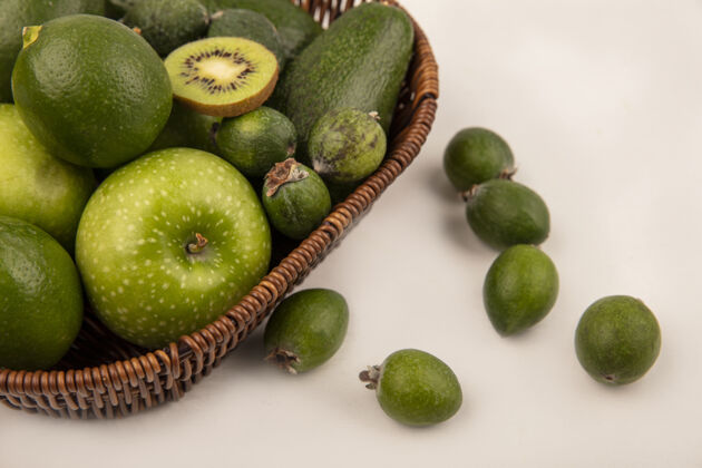 人顶视图绿色水果 如苹果 鳄梨 酸橙和feijoas桶上的白色墙壁肥肉膳食素食