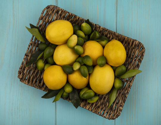 木材顶视图柑橘类水果 如金盏花和柠檬柳条托盘上的蓝色木墙农业景观食物