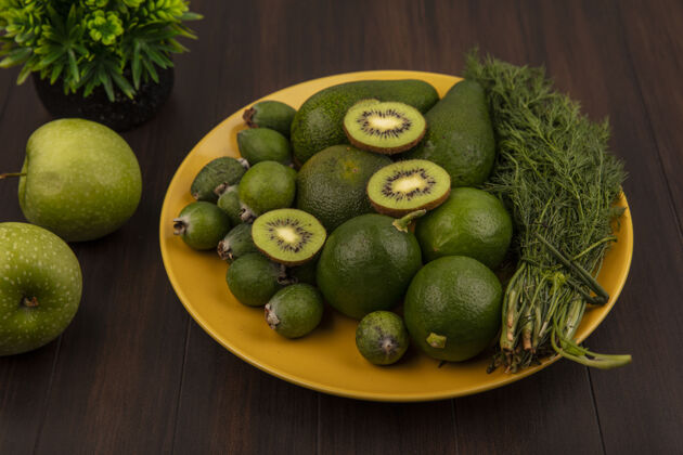 人健康水果的俯视图 如鳄梨 猕猴桃和酸橙 放在木墙上格子布上的黄色盘子上检查酸橙饮食