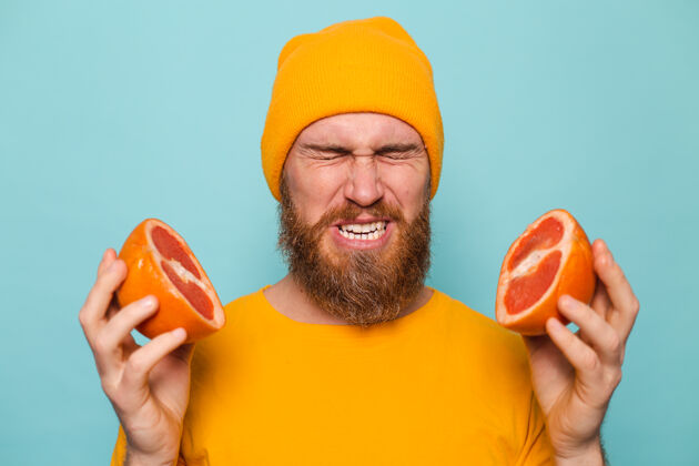 珊瑚留着胡子的欧洲男人穿着黄色衬衫 孤身一人 捧着葡萄柚的味道 皱纹来自苦涩食物早晨有趣