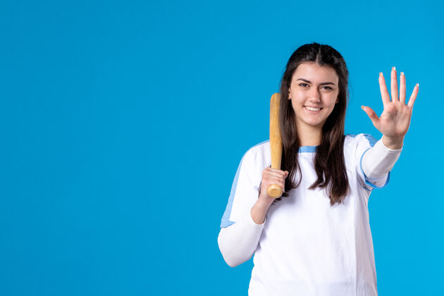 人正面图蓝色墙上拿着棒球棒的年轻女子成人体育棒球