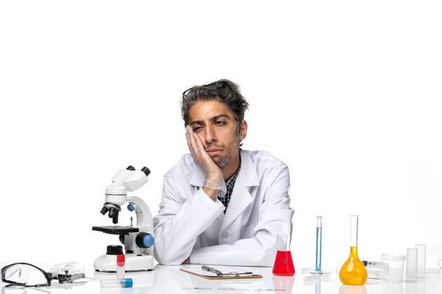 科学正面图身着医学服的中年科学家围坐在桌子旁 带着解决方案和思考外套实验室实验