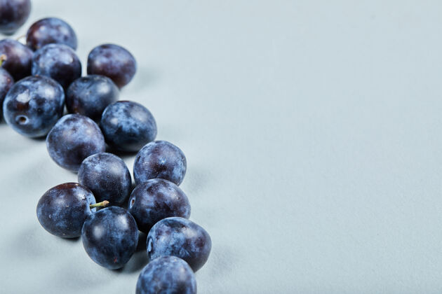 成熟的蓝色背景上的一组新鲜李子健康紫色美味