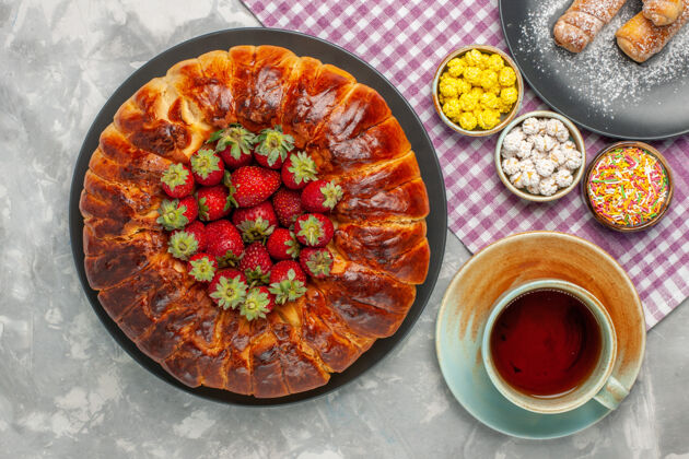 食物俯瞰美味的草莓馅饼与新鲜的红色草莓和一杯茶的白色表面含糖的美味胡椒粉