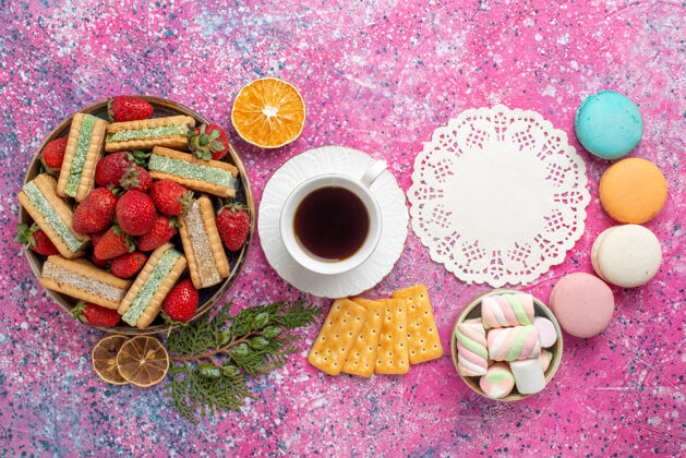 茶俯瞰美味的华夫饼 粉色表面上有一杯茶和新鲜的红色草莓草莓早餐五颜六色