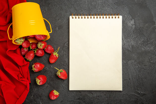 笔记本顶视图新鲜的红色草莓放在深色的水果桌上 浆果成熟了问候语圆锥形食物