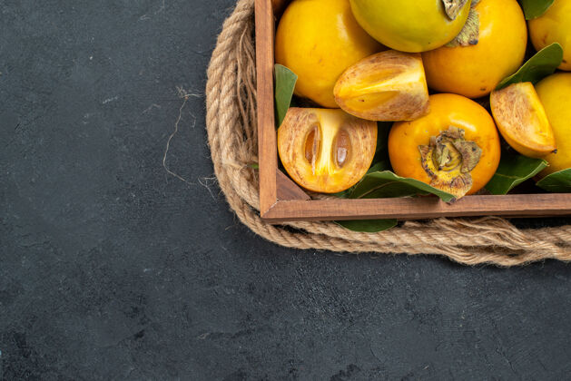 食物顶视图新鲜甜甜的柿子在盒子里放在深色的桌子上品尝成熟的水果黄色盒装健康