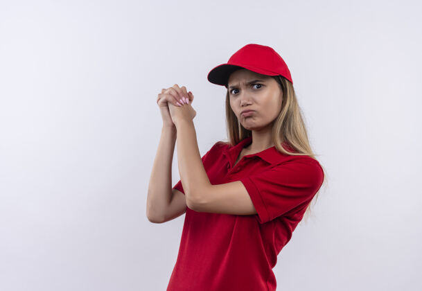送货自信的年轻送货女孩穿着红色制服 戴着帽子 在白色的墙上展示握手的姿势制服手势表演