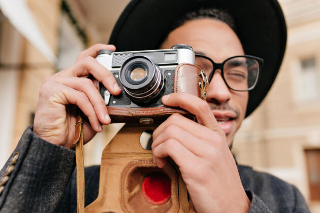 城市戴着优雅眼镜的英俊黑人男子的特写肖像 用相机拍照非洲摄影师在户外工作情感时尚服装