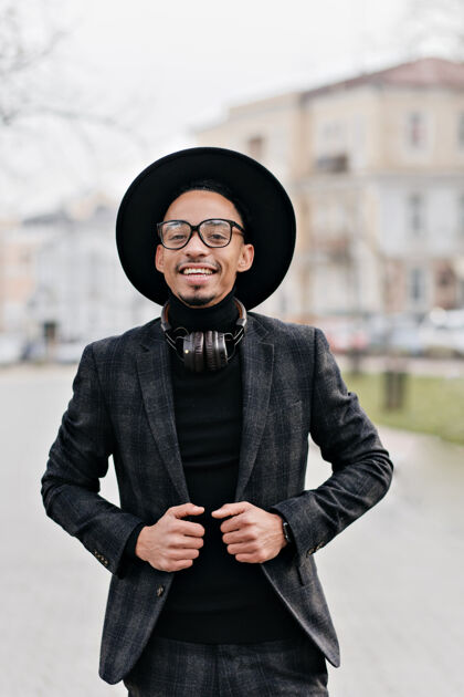 时尚微笑着的戴眼镜的非洲男人自信地站着帅哥的户外画像穿着时尚的格子西装 表达着幸福放松城市微笑