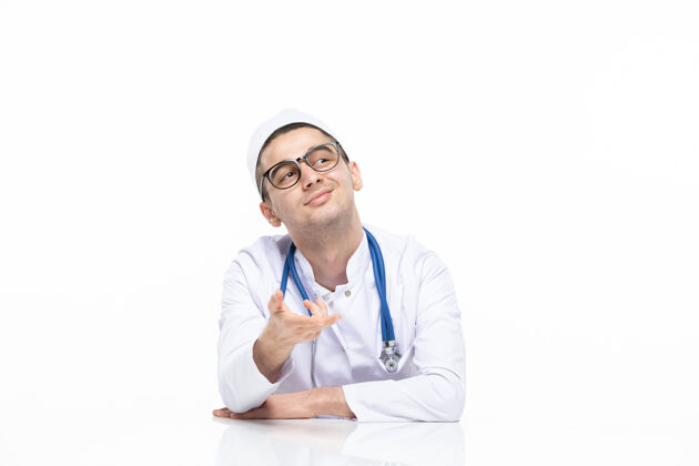 专业正面图：年轻的医生穿着医疗服坐在桌子后面人白人坐姿