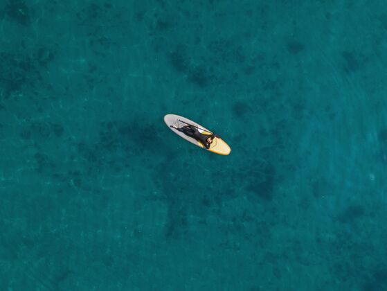运动男人躺在冲浪板上俯视冲浪者海洋季节
