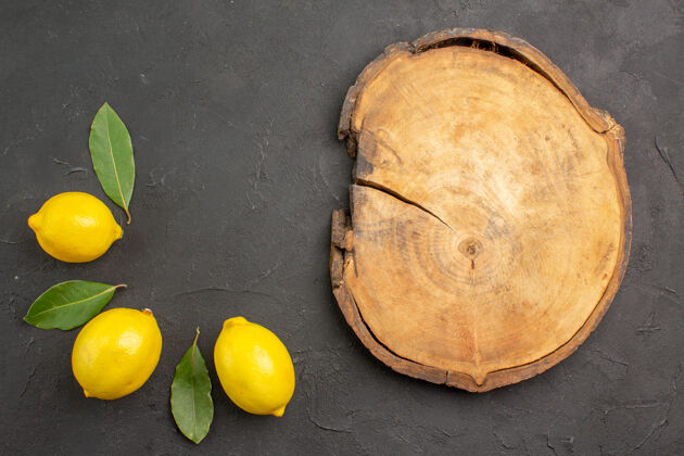 平铺顶视图新鲜酸柠檬和叶子放在深色的桌子上水果柠檬黄色的柑橘顶部柠檬蔬菜