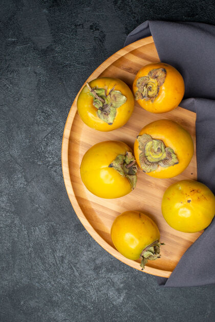 成熟顶视图新鲜柿子成熟甜甜的水果放在深色的桌子上 水果成熟醇厚柿子黄色食物