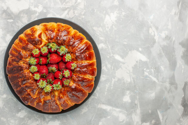 生的白色表面有新鲜红色草莓的美味草莓派俯视图糖果美味盘子