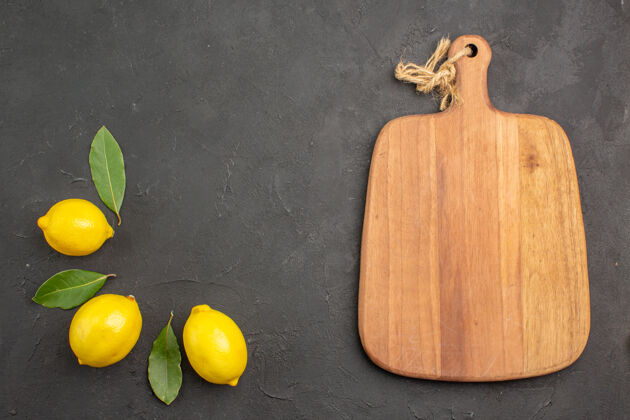 多汁顶视图新鲜酸柠檬和叶子放在深色的餐桌上水果柠檬黄色的柑橘柑橘水果健康