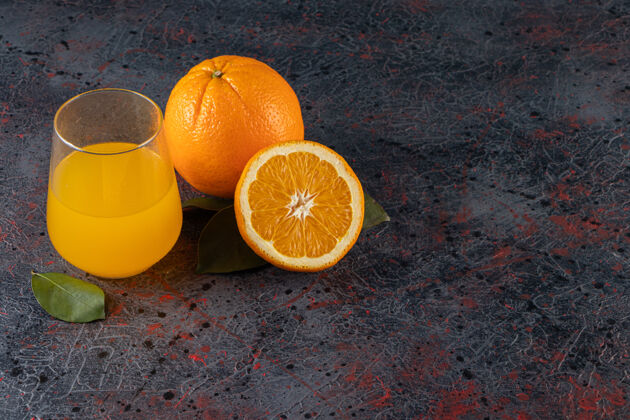 果汁把鲜橙子切成薄片 放在石桌上 放上叶子和一杯果汁颜色酸味果味
