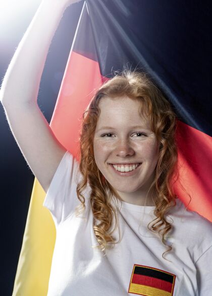 人手持德国国旗的微笑女人的正面图公民足球联赛人