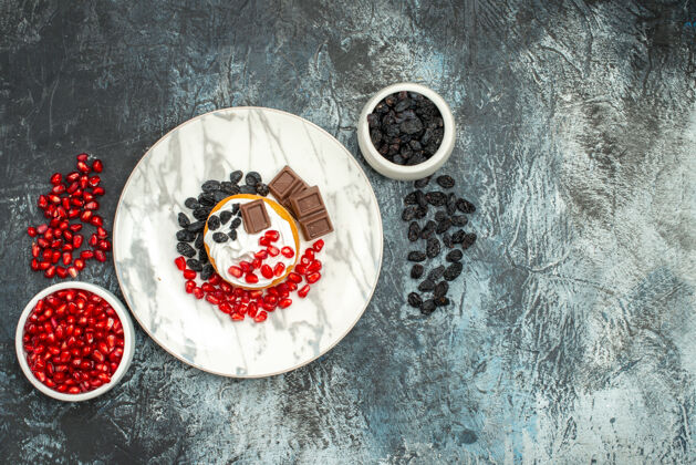 磁盘顶视图美味的奶油蛋糕与巧克力石榴和葡萄干浅黑色的背景背景圆圈瓷器