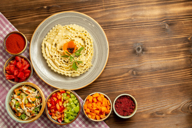 食物顶视图生面团与蔬菜和调味品在一个棕色的表面团生面团用餐盘子碗