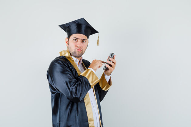 自信年轻人穿着毕业制服 正在用计算器 面带沉思毕业沉思成人