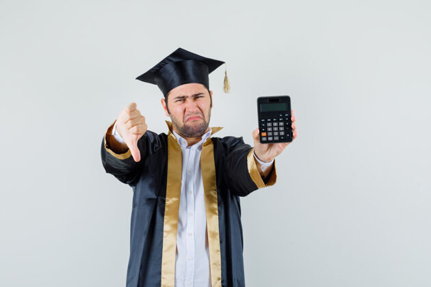 肖像年轻人拿着计算器 穿着毕业生制服 大拇指朝下 看上去很失望前视图衬衫成人休闲