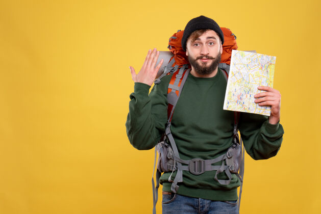 向上旅行概念与自信的年轻人与背包和持有地图显示在黄色成人人物旅行