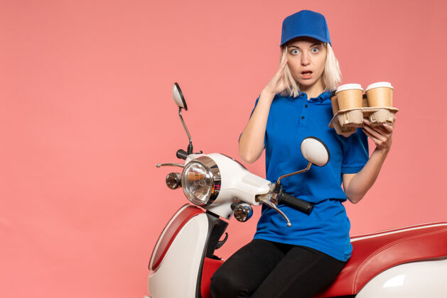 自行车正面图骑自行车的女快递员 咖啡杯放在粉红色的椅子上摩托车女快递杯子