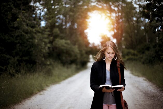 女人女人站在路上和太阳一起读圣经阅读美丽女性