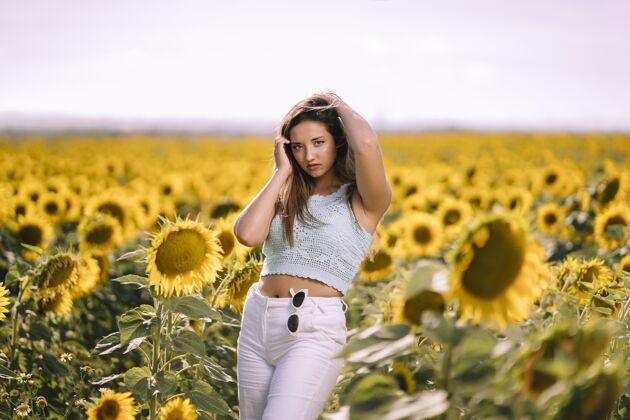 草地在阳光明媚的日子里 一位白人年轻女性在向日葵的田野里摆姿势的水平镜头风景向日葵阳光