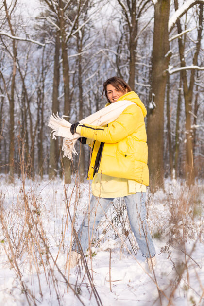 欢呼美丽的年轻开朗的女人在雪景的冬日森林里玩得很开心 穿着暖和的衣服在冬天和雪里快乐公园欢乐美丽