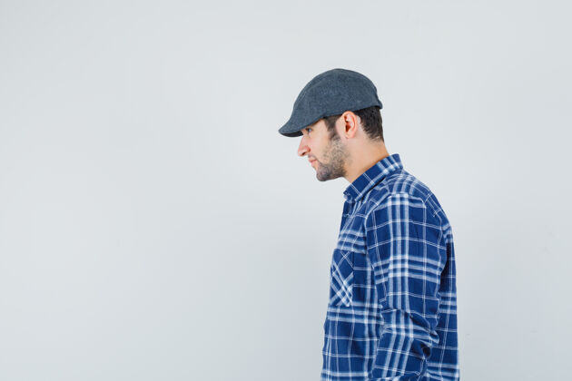 手年轻的男性穿着蓝色衬衫 戴着帽子向前看为您的文字腾出空间休闲年轻男性
