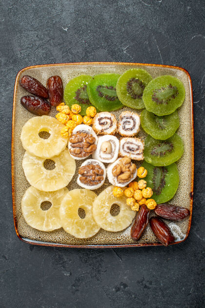 晚餐顶视图切片干果菠萝环和猕猴桃灰色背景干果葡萄干甜酸维生素健康菠萝顶部美食