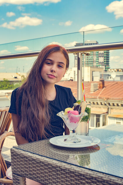 快乐少女开心地笑着 坐在餐厅或咖啡馆吃冰淇淋露台餐桌奶油