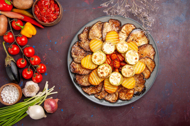 烹饪顶视图烤蔬菜土豆和茄子与不同的调味品在一个黑暗的桌子上烘焙盘子桌子