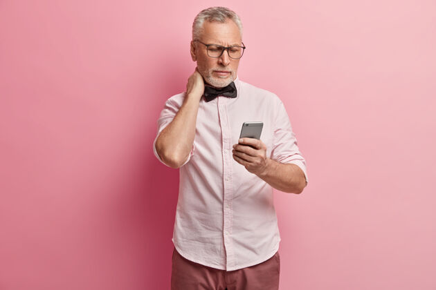 人穿粉红色衬衫和黑色领结的老人拿着电话男肖像人