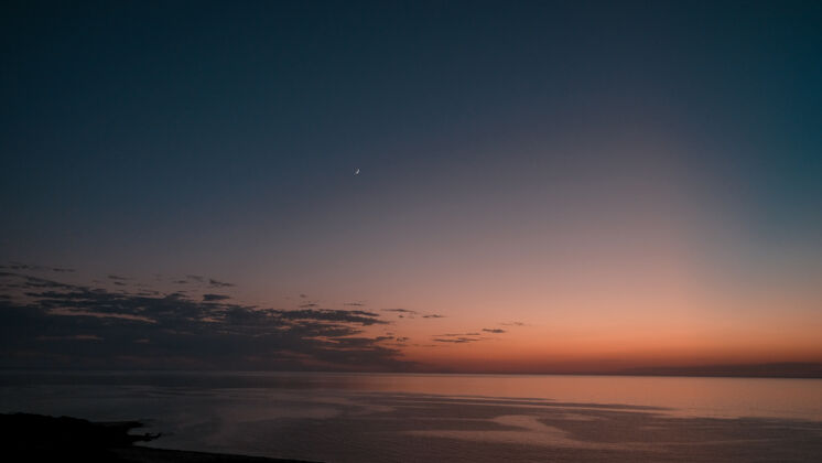 海岸橙色日落时美丽海景的惊人镜头五颜六色夜晚光