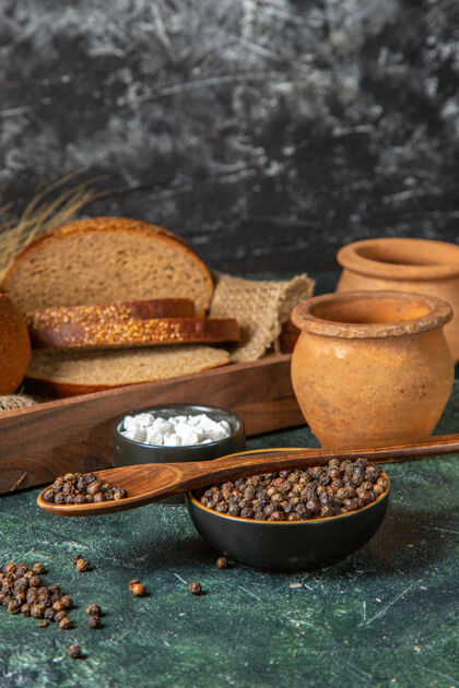 黑面包正面图是整个切好的新鲜黑面包 放在毛巾上 棕色木盒 陶器 香料 深色混合色表面面包早餐木材