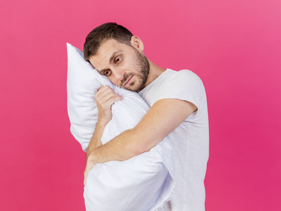 拥抱悲伤的年轻病夫抱着粉红色背景的枕头悲伤疾病抱枕