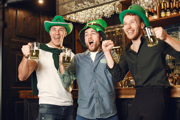绿帽子戴绿帽子的男人朋友们庆祝圣帕特里克节在酒吧庆祝酒吧干杯年轻
