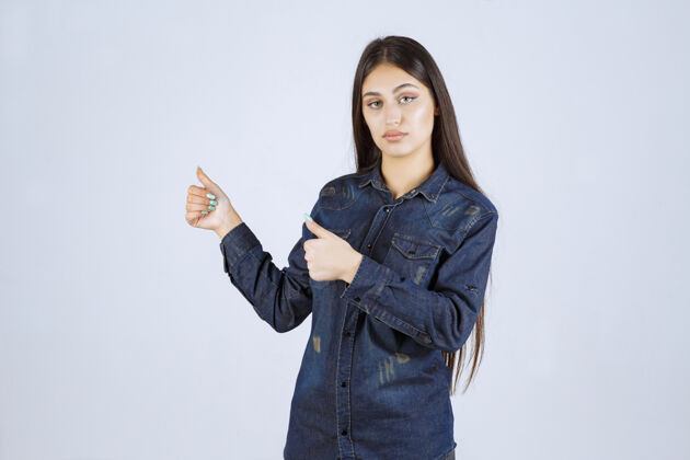 人类穿着牛仔衬衫的年轻女子 手上有积极的手势姿势交易休闲