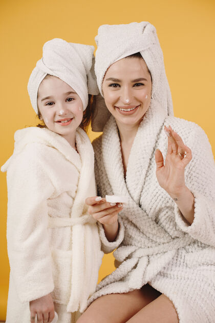 魅力妈妈带着女儿女孩们穿着白色浴衣妈妈教女儿化妆婴儿浴袍休闲