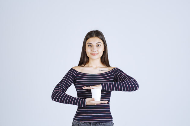 工人穿着条纹衬衫的女孩双手捧着一个塑料咖啡杯年轻人成人聪明