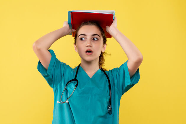 女人正面图女医生穿着医用衬衫手持纸条 彩色病毒健康情感covid-19大流行制服黄色便条剪贴板