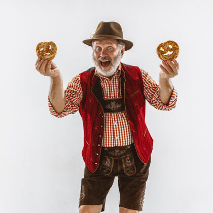 娱乐啤酒节老人的画像戴着帽子 穿着传统的巴伐利亚服装 手里拿着椒盐卷饼胡子帽子乐趣