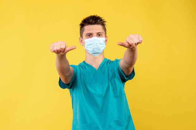 健康黄墙上的男医生穿着医疗服 戴着无菌口罩脸前面成人