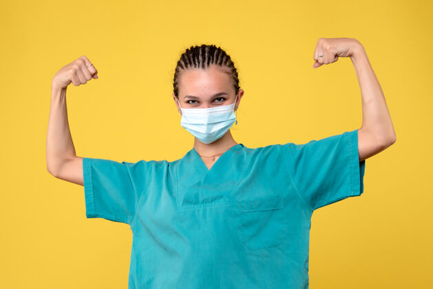 弹性身着医疗服 戴着消毒口罩的女医生正俯视黄色墙壁肖像正面医疗