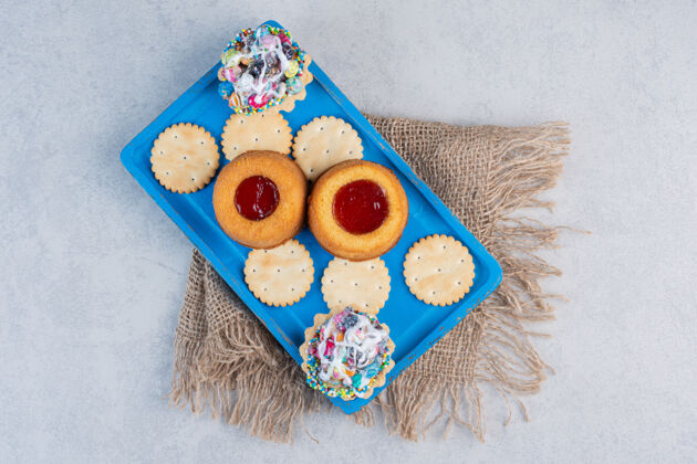 烘焙食品饼干 纸杯蛋糕和果冻蛋糕放在大理石桌上的蓝色盘子里填充美味甜点