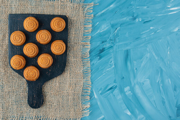 零食麻布上放着一块黑色木板 上面放着香甜可口的圆饼干圆形饼干蛋糕